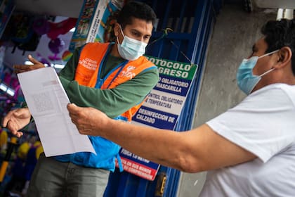 Personal de seguridad revisa el certificado de vacunación obligatorio a un ciudadanos en Lima, Perú