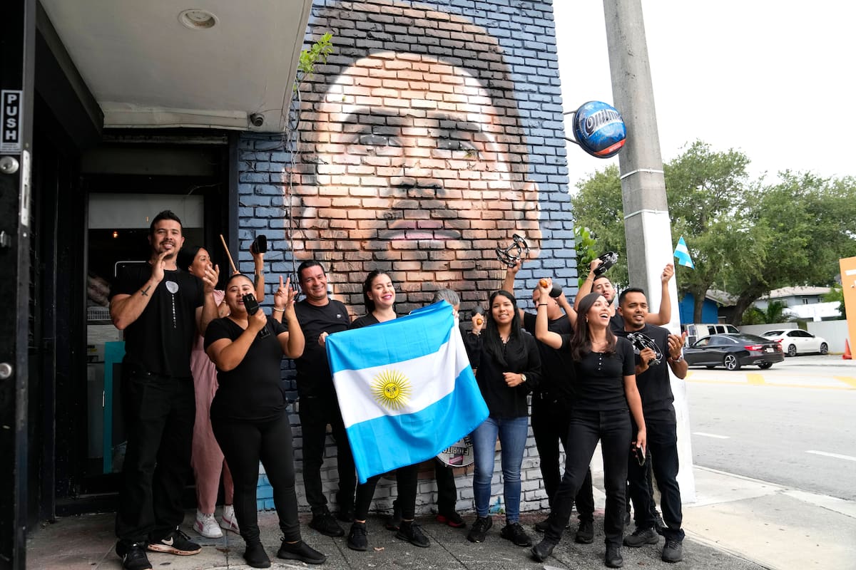 Personal del restaurante Fiorito porta una bandera de Argentina frente a un mural de Lionel Messi en Miami, el miércoles 7 de junio de 2023 (AP Foto/Lynne Sladky)