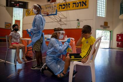 Personal médico hace pruebas de coronavirus a niños israelíes en una cancha de basquetbol convertida en centro de pruebas en Binyamina, Israel