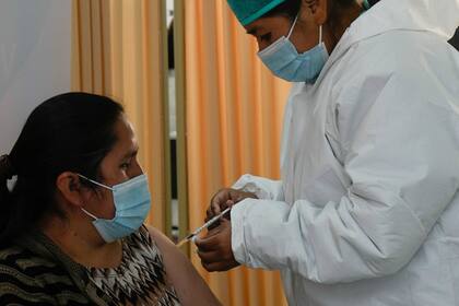 Personal médico vacuna a una mujer con el fármaco contra el COVID-19 Sputnik V en la Universidad Unifranz, durante una campaña para mayores de 30 años, en La Paz, Bolivia, el jueves 24 de junio de 2021. (AP Foto/Juan Karita)