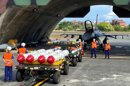 Personal militar junto al Harpoon A-84, misiles antibuques y misiles aire-aire AIM-120 y AIM-9 preparados para ejercicios de carga de armas frente a un avión de combate F-16V en la base aérea de Hualien, Taiwán, el 17 de agosto de 2022. (AP Foto/Johnson Lai, Archivo)