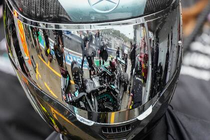 Personal técnico de Mercedes aparece reflejado en un casco mientras trabaja en el auto del piloto finlandés Valtteri Bottas, en el garaje de la escudería en el Autódromo de Sochi, Rusia, el jueves 23 de septiembre de 2021. (AP Foto/Sergei Grits)