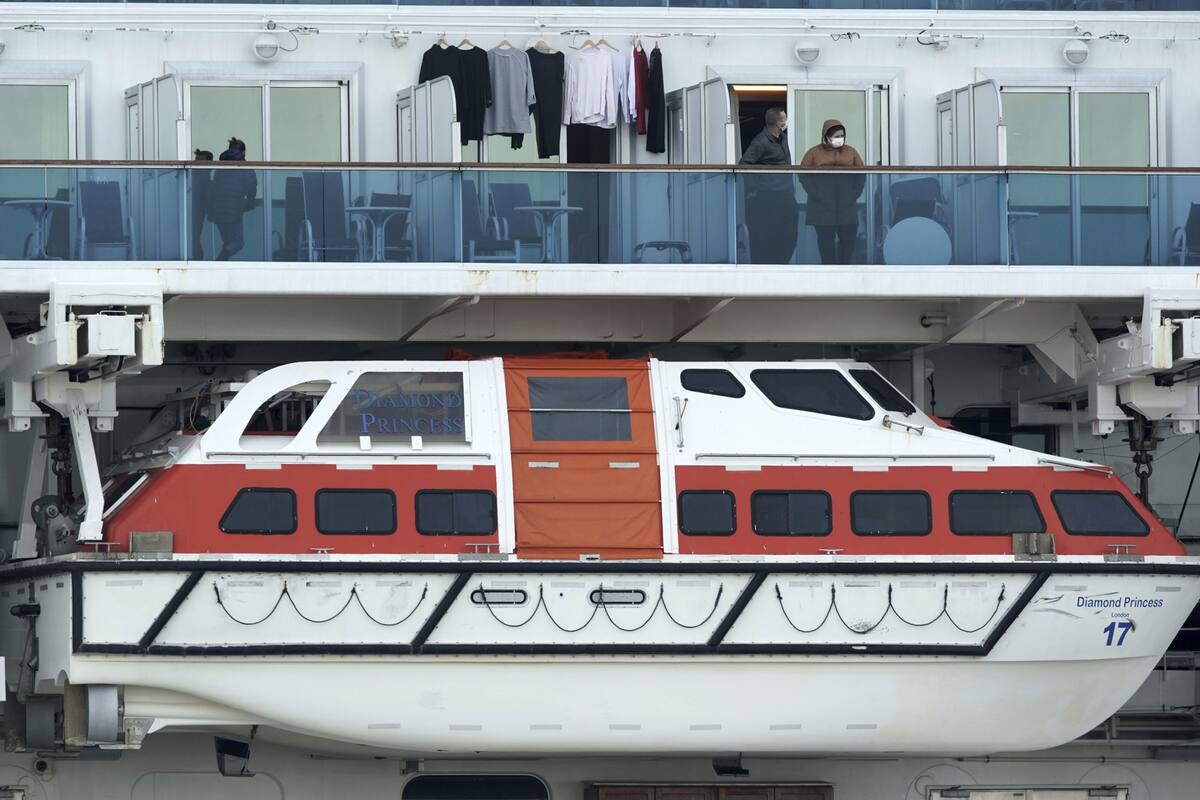 Personas a bordo del Diamond Princess se asoman al balcón de sus camarotes