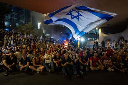 Personas bloquean un camino durante una protesta para exigir un acuerdo que lleve a la liberación inmediata de los rehenes que mantiene Hamás en la Franja de Gaza, el domingo 1 de septiembre de 2024, en Tel Aviv, Israel. (AP Foto/Ohad Zwigenberg)
