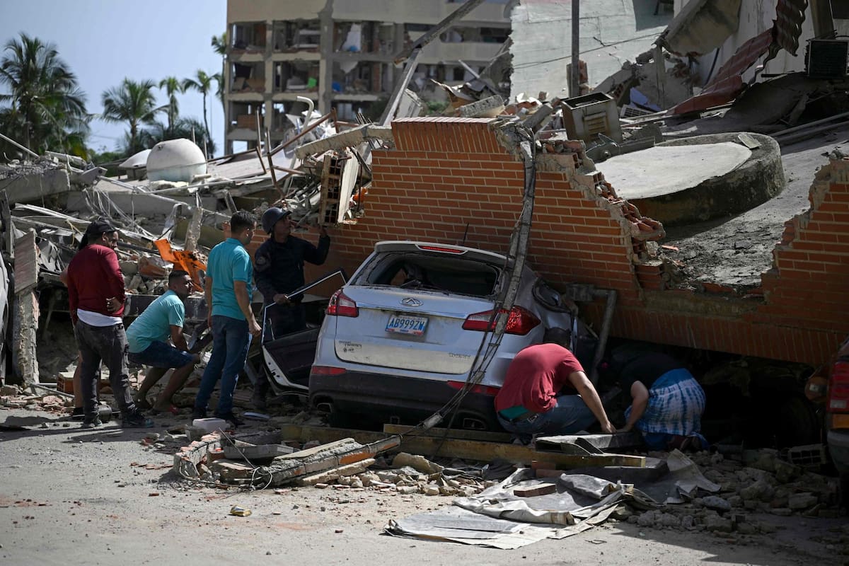 Personas buscan entre los escombros alrededor de un auto atrapado bajo los restos colapsados de un edificio residencial tras un terremoto en Catia La Mar