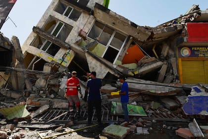 Personas buscan sobrevivientes entre los escombros de un edificio derrumbado tras un terremoto en Pereira, Colombia