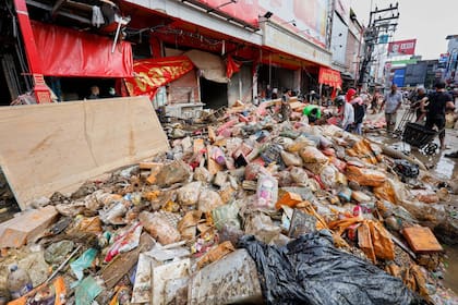 Personas caminan cerca de mercancías dañadas por las inundaciones en la provincia de Songkhla, en el sur de Tailandia, el sábado 29 de noviembre de 2025