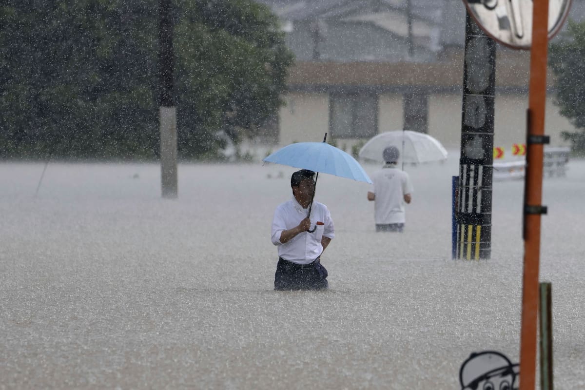 Personas caminan en una calle inundada por las fuertes lluvias, el lunes 10 de julio de 2023, en Kurume, en la prefectura de Fukuoka, en el sur de Japón.