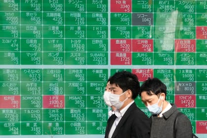 Personas caminan frente a un tablero electrónico de operaciones bursátiles que muestra los precios de las acciones de Japón, en una firma de inversiones en Tokio, el 8 de diciembre de 2022. (AP Foto/Shuji Kajiyama)