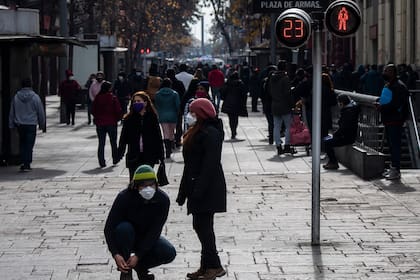Personas con máscaras faciales caminan en la Plaza de Armas en Santiago, el 6 de julio de 2020, en medio de la pandemia de coronavirus