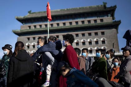 Personas con tapabocas llegan a la calle Qianmen para comprar durante el feriado nacional de la "Semana Dorada" hoy en Pekín