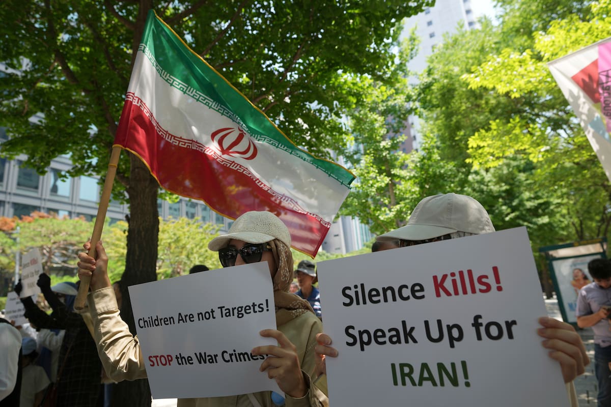 Personas con una bandera iraní y con carteles se manifiestan para exigir un alto a la guerra entre Israel e Irán, en Seúl, Corea del Sur