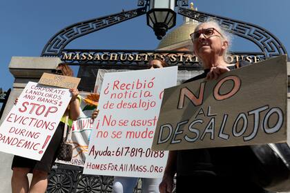 Personas de una coalición por la justicia en las viviendas llevan carteles de protesta contra los desalojos durante una conferencia de prensa junto a la legislatura de Massachusetts, el 30 de julio del 2021. en Boston. (AP Foto/Michael Dwyer)