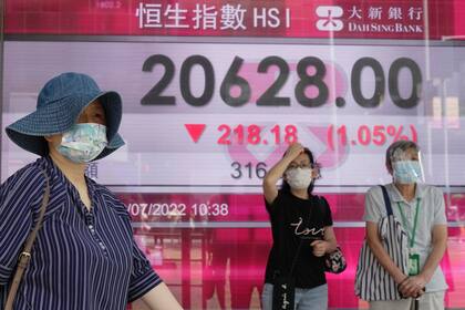 Personas frente a una cartelera financiera en Hong Kong el 19 de julio de 2022. (Foto AP/Kin Cheung)