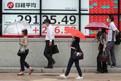 Personas frente a una cartlera financiera en Tokio el 17 de agosto de 2022. (Foto AP/Eugene Hoshiko)
