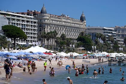 Personas nadando en el mar frente al hotel Carlton previo a la 74a edición el Festival Internacional de Cine de Cannes, en el sur de Francia el 5 de julio de 2021. El Festival de Cine de Cannes se celebrará del 6 al 17 de julio de 2021. (Foto AP/ Brynn Anderson)