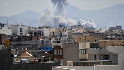 Personas observaron desde una terraza cómo una columna de humo se elevaba tras el ataque en Teherán, Irán (Foto AP/Vahid Salemi)
