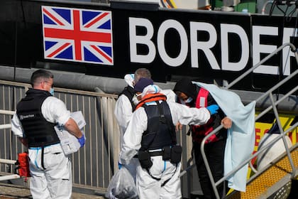Personas que se cree son migrantes desembarcan el jueves 16 de septiembre de 2021 de un barco patrulla de la Fuerza Fronteriza Británica en el puerto de Dover, Inglaterra, después de que los rescataran de una lancha inflable en el canal de la Mancha. (AP Foto/Alastair Grant)
