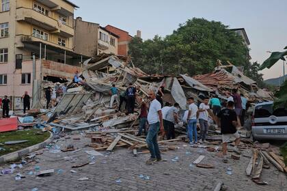 Personas retiran los escombros de un edificio derrumbado tras un sismo en Sindirgi, noroeste de Turquía