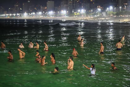 Personas se bañan de noche en la playa de Arpoador, en Río de Janeiro, para mitigar el calor extremo