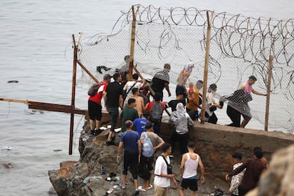 Personas se reúnen junto a la valla, cerca del lugar de los enfrentamientos, próximo a Fnideq (Castillejos), en la frontera entre Marruecos y España