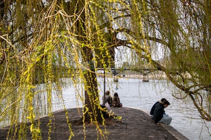 Personas sentadas al borde del Sena junto al Pont Neuf en París, 20 de marzo de 2023. En 2024, el río servirá como sede para los triatletas olímpicos y los nadadores de distancia. (James Hill/The New York Times)