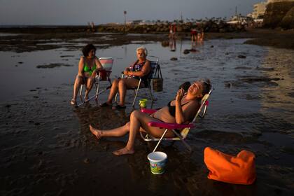 Personas toman el sol en una playa en Chipiona, ubicado en la costa del Atlántico, en la provincia Cadiz, España, el viernes 9 de julio de 2021. (AP Foto/Emilio Morenatti)