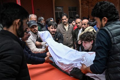 Personas transportan el cadáver de una víctima de un atentado suicida en una mezquita chiita en Islamabad