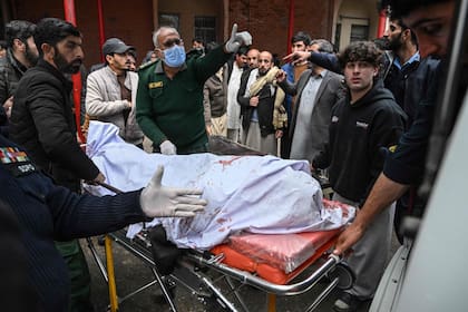 Personas transportan el cadáver de una víctima de un atentado suicida en una mezquita chiita en Islamabad