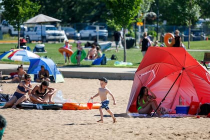 Personas tratan de escapar del calor en una playa en Chestermere, Aberta, Canadá, el martes, 29 de junio del 2021. La ola de calor que azota el oeste de Canadá ha causado temperaturas récord en varias áreas.  (Jeff McIntosh/The Canadian Press vía AP)