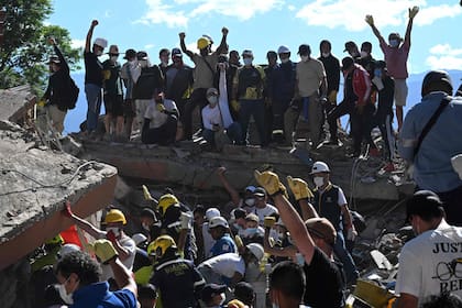 Personas y rescatistas buscan sobrevivientes entre los escombros de un edificio derrumbado tras un terremoto en Cali, Colombia