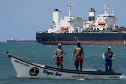 Pescadores pasan junto a un buque petrolero en el golfo de Venezuela frente a la costa de Punta Cardón, Venezuela