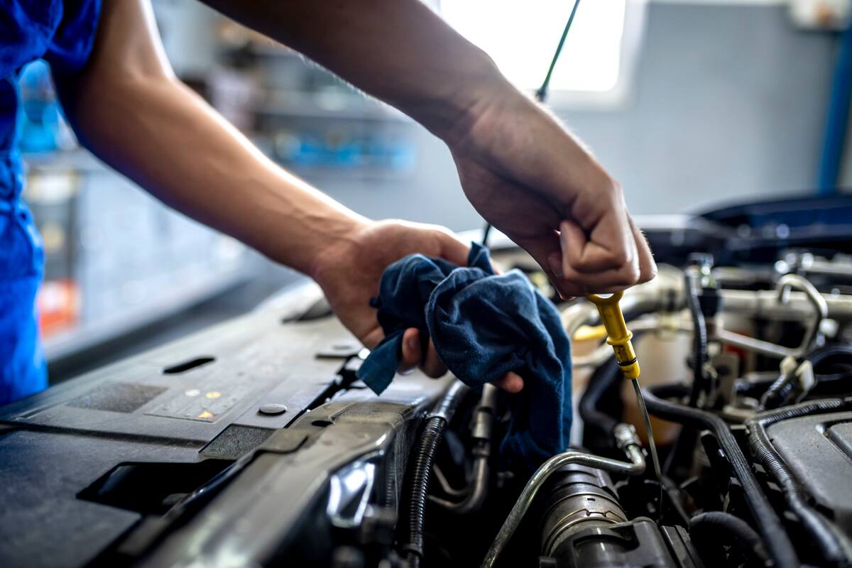 Photo of Unrecognizable male mechanic measuring the oil level of an engine at an auto shop. Mechanic checking the oil level in a car service garage. Repairing engine at a service station. Car repair."r"n.