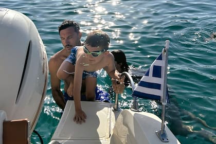 Pico y Noah –con antiparras– vuelven a subir a la lancha después de un baño en el mar