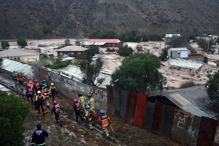 Picture released by ATON of a rescue workers walking at a rural area in La Serena, Coquimbo region, Chile, on July 21, 2026, following severe weather conditions. Heavy rains in Chile have killed at least 13 people and left more than 60,000 others cut off due to washed out roads, government officials said in a report on July 21, 2026, as the recovery effort focused on restoring basic services. (Photo by Alejandro PIZARRO / ATON CHILE / AFP) / - Chile OUT / RESTRICYED TO EDITORIAL USE - MANDATORY CREDIT AFP PHOTO / ATON / ALEJANDRO PIZARRO - NO MARKETING NO ADVERTISING CAMPAIGNS -DISTRIBUTED AS A SERVICE TO CLIENTS