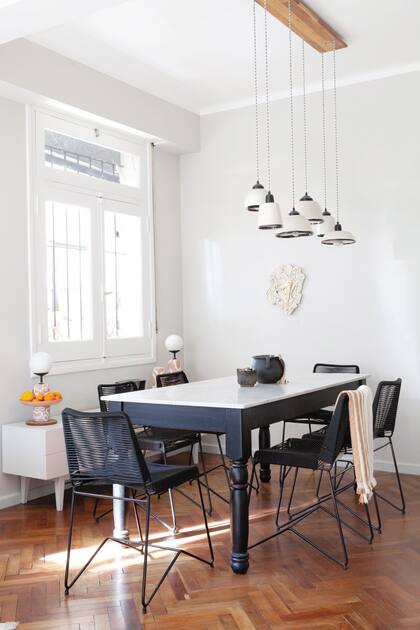 Pintaron de negro la base de la mesa heredada y así destacaron el sector del comedor. Sobre la consola, antes azul y ahora del mismo color que la pared, lámparas de la serie ‘Con foco en la tierra’ (Cecilia Nigro).