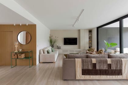 Piso de porcelanato San Pietro Naturale. La manta sobre el sillón, traída de un viaje. Ennmarcando la TV mueble de MDF laqueado color arena (Estudio Cielo Pipkin). Floreros y candelabros (Component New House).