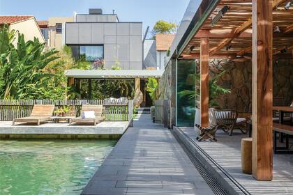 Piso de pórfido cortado al disco (Lajas Quilmes). Reposeras de incienso (Las Marinas). Deck y ducha en anchico sin tratamiento, añejado el sol. Revestimiento de pileta en piedra hijau (ABC Design Stone).