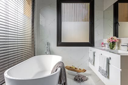 Piso y paredes de porcelanato ‘Bianco Apuano’ (Vite). Mueble con mesada de Corian. Toallas de algodón, sales de baño, jabón y cepillo (Claudia Adorno). Cortinas de tablas de PVC (Alix Ruiz Duggan).