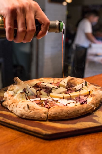Pizza blanca de fior di latte, porchetta con chili, brie, pistachos y reducción de aceto.