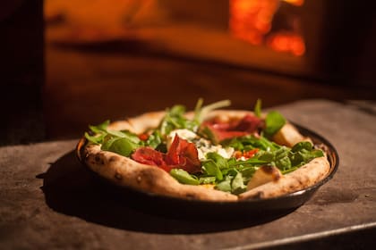Pizza de bresaola y rúcula con fior di latte, salsa de tomate, aceitunas y alcaparras.