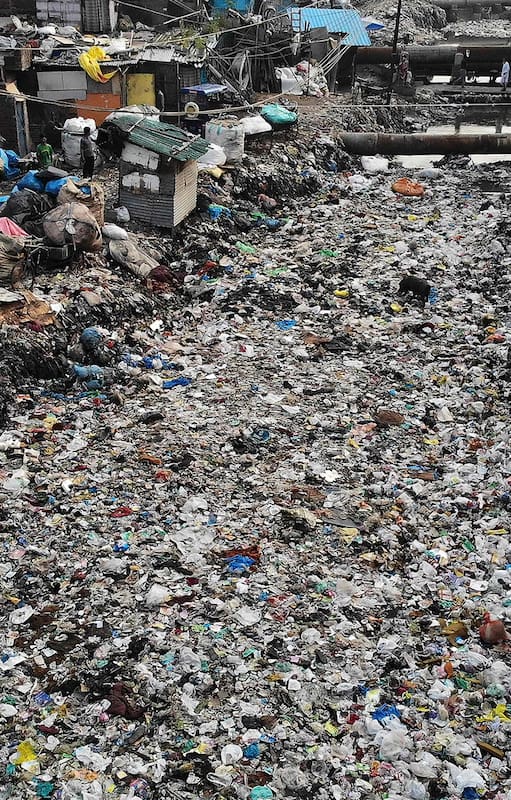 (FILES) In this file photo taken on October 04, 2019 In this aerial photo taken on October 4, 2019 children (L) stand near a polluted sewage drain canal covered in garbage in a low-income neighborhood in New Delhi. (Photo by Noemi Cassanelli / AFP)