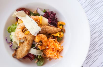 Ensalada fresca de camarones y brie en colchón de rúcula, con almendras y tomates secos.