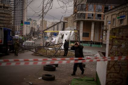 Oficiales de policía inspeccionan el área después de un ataque ruso en Kiev
