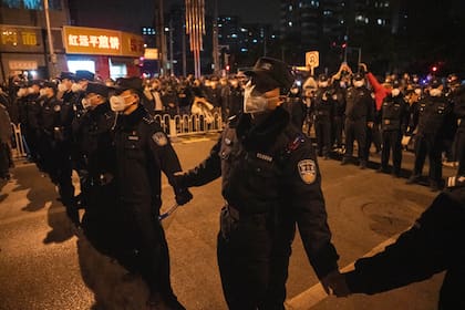 Policías chinos forman una línea para detener una marcha de manifestantes en Pekín
