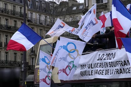 Policías de París se manifiestan con banderas que convierten los anillos olímpicos en esposas, 10 de enero de 2024. Los agentes que cumplan funciones en los Juegos Olímpicos de París recibirán pagos especiales, se informó el 30 de enero de 2024. (AP Foto/Michel Euler)