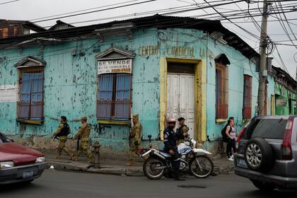 Policías de patrulla pasan junto a un vehículo que lleva boletas a un centro electoral el día antes de las elecciones generales en San Salvador, El Salvador, el sábado 3 de febrero de 2024. (AP Foto/Moisés Castillo)