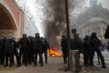 Policías están parados junto a una barricada en llamas durante una manifestación en París, el sábado 11 de marzo de 2023. (AP Foto/Lewis Joly )