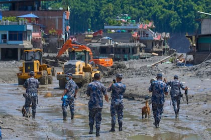 Policías nepalíes observan mientras la maquinaria retira escombros tras inundaciones repentinas en el distrito de Nuwakot, en Nepal, el 27 de agosto de 2026. (AP Foto/Niranjan Shrestha)