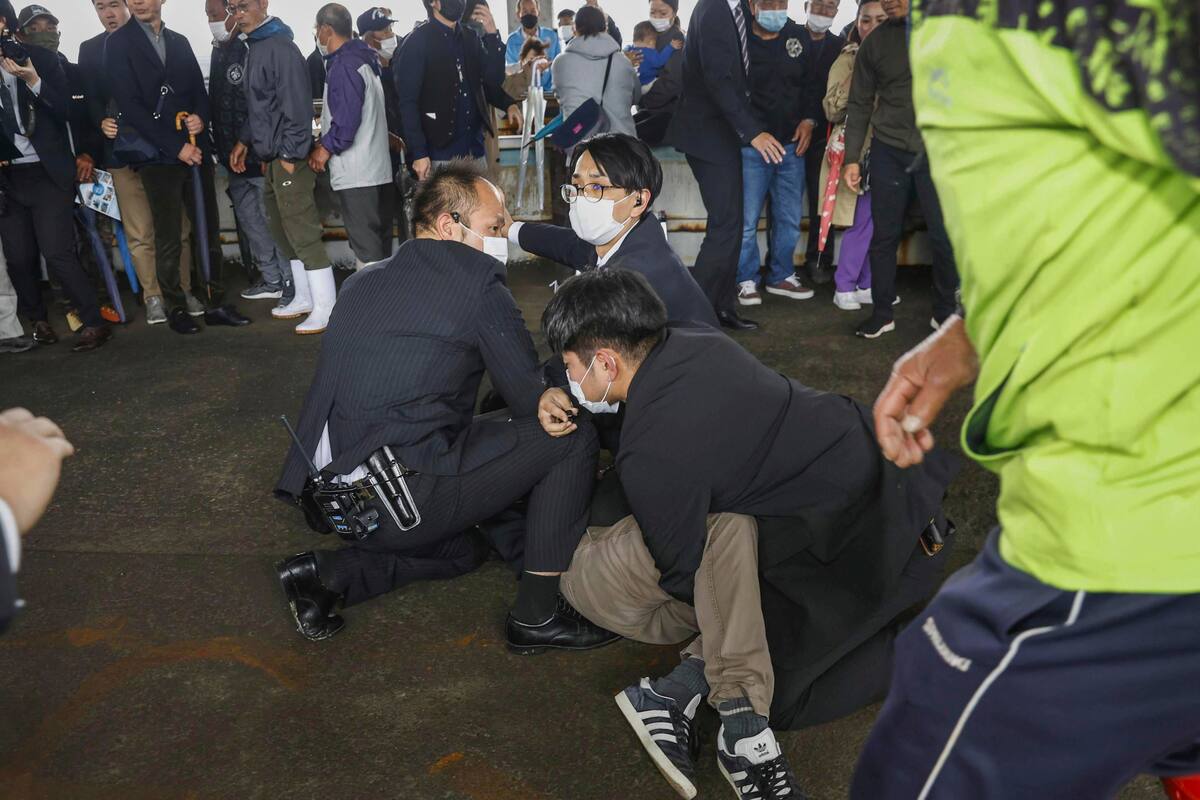 Policías someten contra el piso a un hombre que al parecer lanzó una bomba de humo durante la visita del primer ministro Fumio Kishida a un puerto en la prefectura de Wakayama, oeste de Japón, el sábado 15 de abril de 2023.